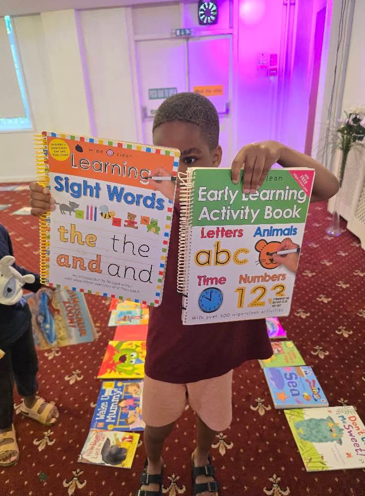 Child holding learning books at community event